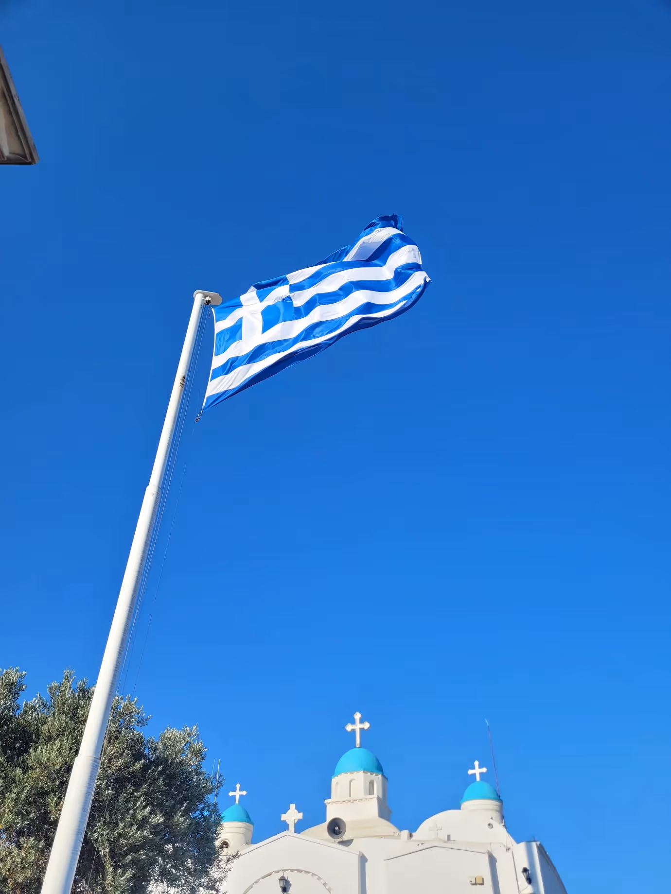 The Greek flag flying beside the whitewashed Chapel of St. George at the summit of Lycabettus Hill Athens